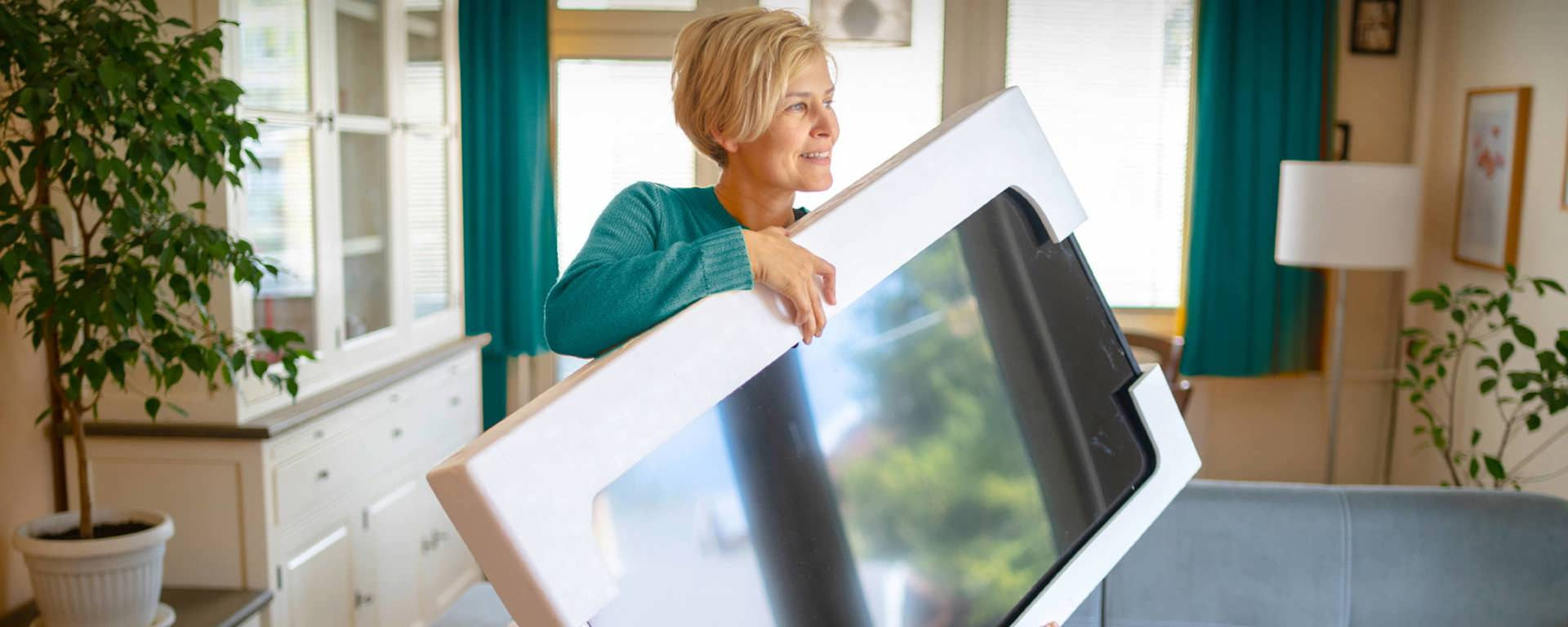 Woman in teal coloured top holding a new TV thanks to Instant Finance cash loans