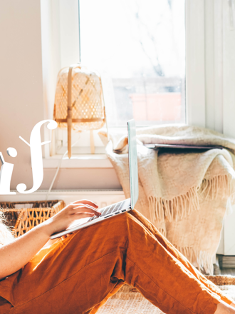 Girl sitting in her bedroom working on laptop