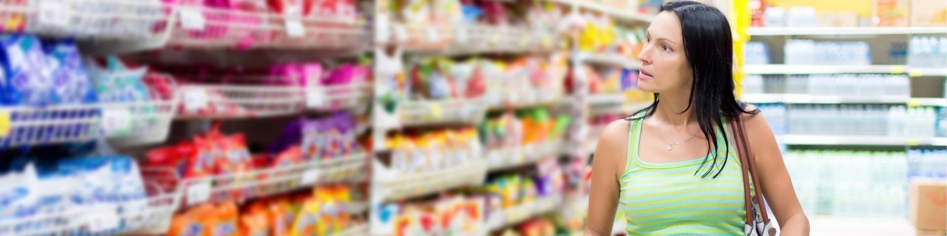 Woman comparing prices in a supermarket aisle