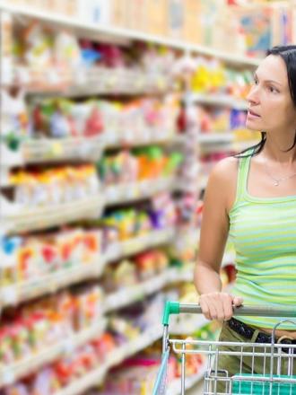 Woman in supermarket thinking about the cost of living payment due to food prices