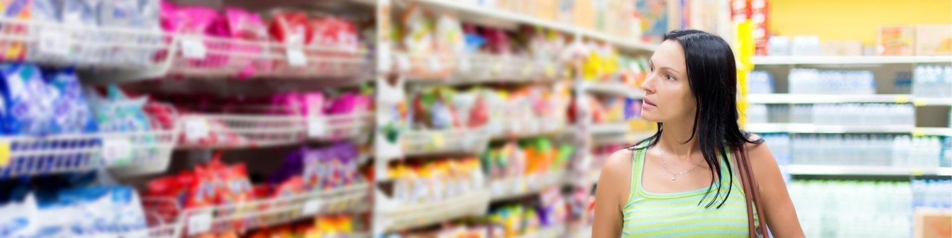 Woman in supermarket thinking about the cost of living payment due to food prices