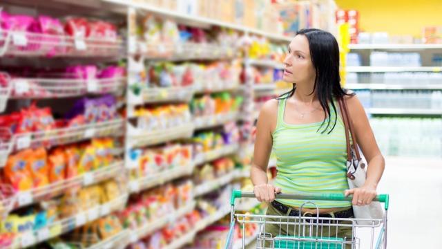 Woman in supermarket thinking about the cost of living payment due to food prices