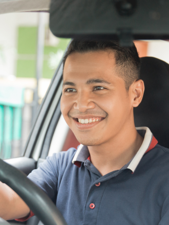 Man in blue shirt driving his car after securing vehicle finance.