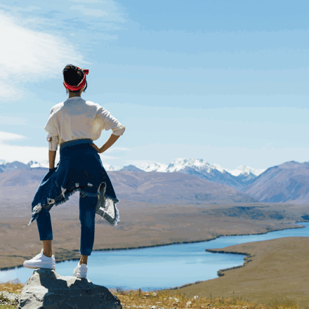 Woman looking out from a cliff top at a mountain range in New Zealand. Nationwide personal loans available at Instant Finance