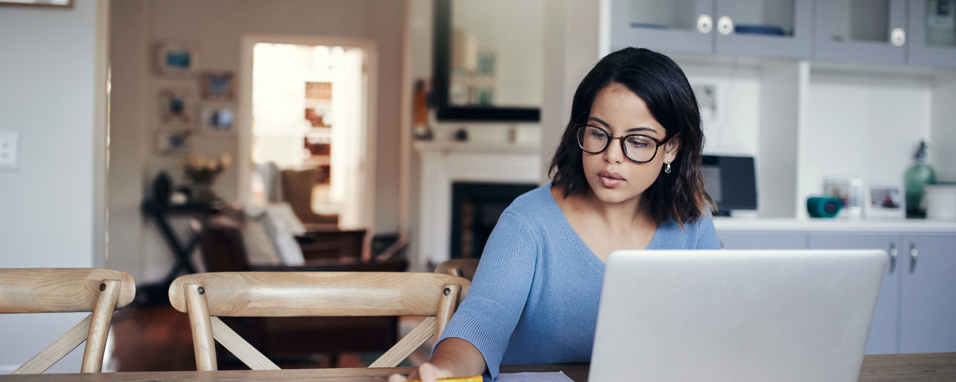 Woman in blue top on laptop computer and calculator working out her financial health