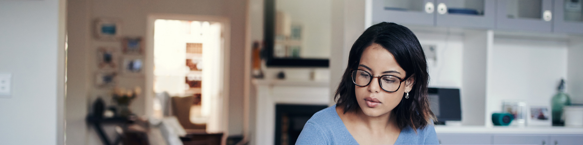 Woman in blue top on laptop computer and calculator working out her financial health
