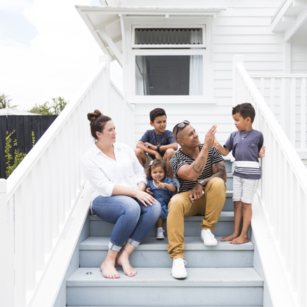 Family sitting on steps outside home, thinking about Life and Funeral Insurance