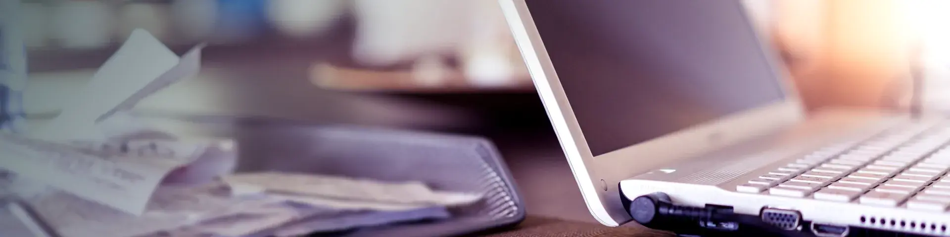 Receipts piled in a desk tray next to an open laptop